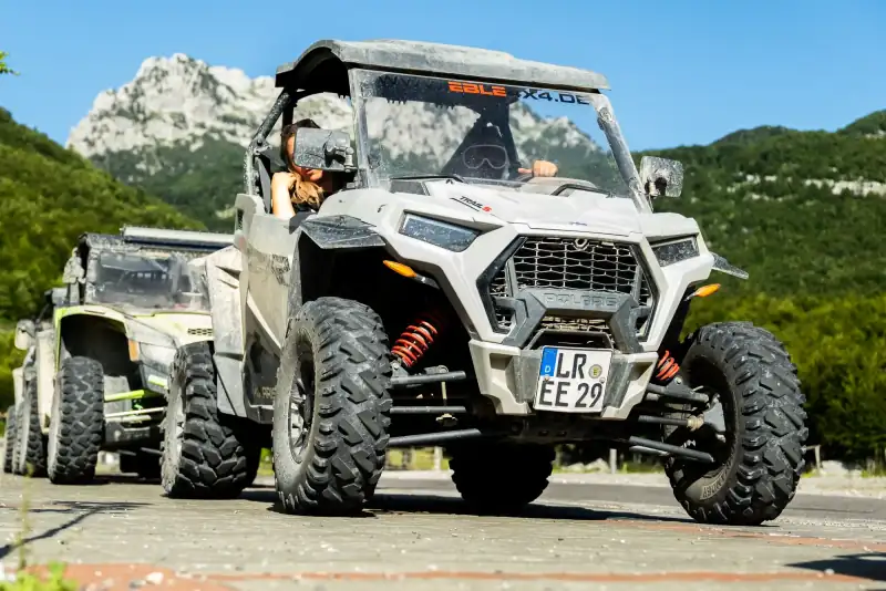 Buggy-Konvoi auf einer Bergstraße vor einem Felsmassiv